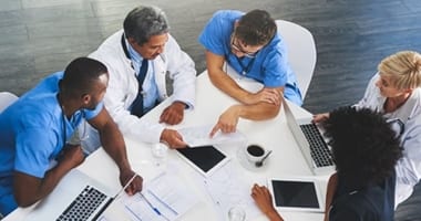 A group of medical workers sitting at a table reviewing paperwork.