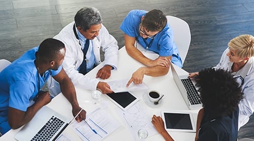 A group of medical workers sitting at a table reviewing paperwork.