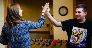 Women and young man giving each other a high-five.