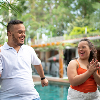 Young couple laughing and clapping in backyard.