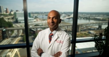 Doctor taking a picture in his office with a cityscape background.