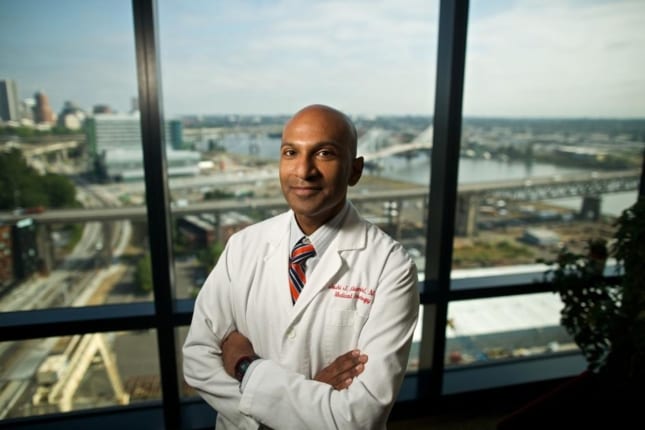 Doctor taking a picture in his office with a cityscape background.