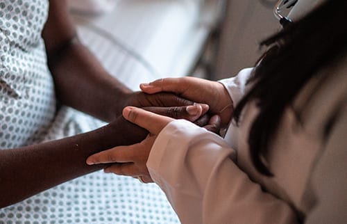 A doctor holding their patient's hands