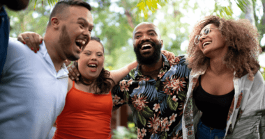 A group of four people smiling and standing with their arms wrapped around each other