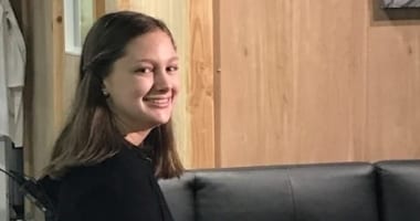 Young girl smiling at the camera sitting on a sofa.