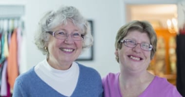 Senior mother and adult child smiling in their home