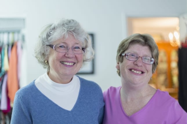 Senior mother and adult child smiling in their home