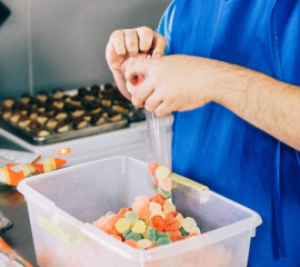 Hands putting candy into a bag.