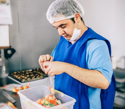 young adult working at a candy factory wearing a hair net.