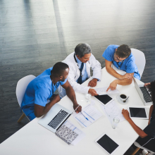 A group of medical workers sitting at a table reviewing paperwork.