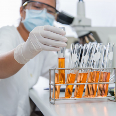 A scientist wearing a mask and handling a test tube.